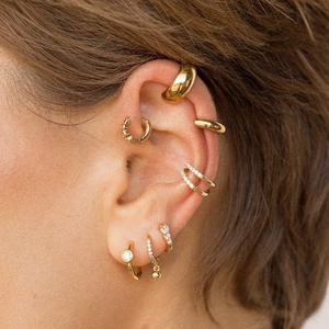 Close-up of gold C-shaped stainless steel hoop earrings and zircon ear cuffs on model