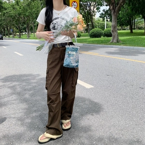 Outdoor lifestyle shot of a woman holding a blue floral handbag with pink flowers