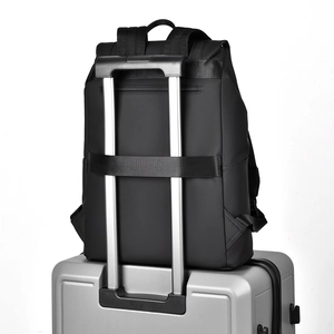 Black business laptop backpack with luggage strap mounted on a silver suitcase handle