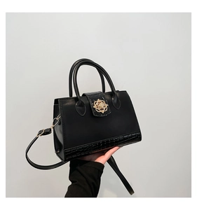 Gros plan du sac à main en cuir PU noir avec motif crocodile et boucle fleurie dorée