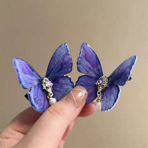 Detail of purple butterfly hair clip with fine wing texture, purple gem, and white pearl