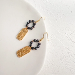 Detailed close-up of bohemian gold earrings featuring engraved sun, moon and star motifs
