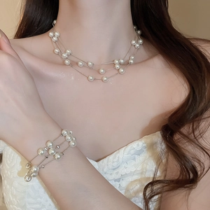 Detailed close-up of multi-layer white pearl necklace and matching double bracelet set