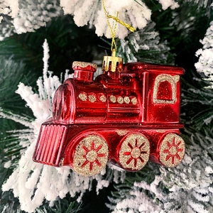 Nahaufnahme einer roten Lokomotive als Weihnachtsbaumschmuck mit Goldglitzer am Zweig