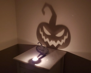Close-up of Halloween pumpkin shadow projector with tea light candle on desk