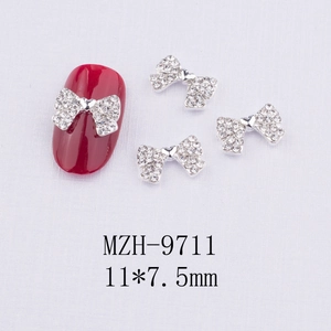 Détail d'un bijou d'ongle nœud argenté 11x7,5mm orné de strass brillants et élégants