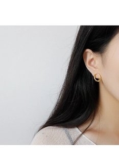 Close-up of minimalist gold oval geometric earrings on model for elegant styling