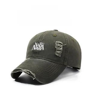 Detailed view of embroidery and distressed holes on an olive denim baseball cap