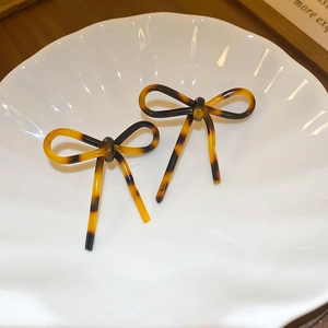 Close-up of leopard print acetate bow hair clips in a white shell-shaped porcelain dish