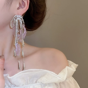 Detail of silver long tassel earrings with lavender stones and rhinestone bow motif