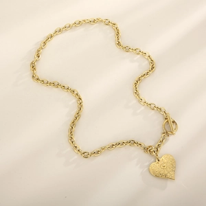 Detail of gold heart pendant necklace with embossed pattern and stylish OT toggle clasp