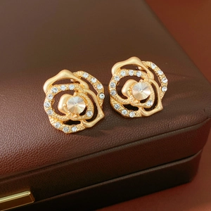 Detailed close-up of gold rose-shaped stud earrings with sparkling pave rhinestones