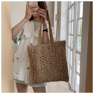 Detail of hand-woven star pattern on straw tote bag with brown leather straps