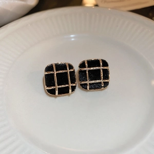 Detail of black flocked heart earrings with gold trim on white ceramic plate