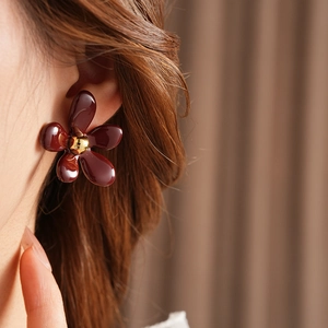 Close-up of model wearing dark brown flower earrings with golden bead center accents