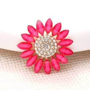 Macro detail of pink sun flower charm with white rhinestones and golden base setting