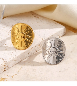Detailed view of sun face embossed rings in gold and silver finish on textured stone