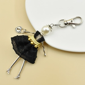 Detail of handmade doll keychain featuring white pearl head and black polka dot mesh skirt