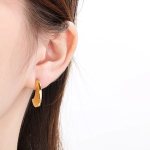 Gros plan d'une boucle d'oreille en chaîne en U plaquée or 18 carats sur un modèle