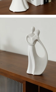 Close-up of matte white ceramic abstract sculpture with grainy texture on a dark wood surface