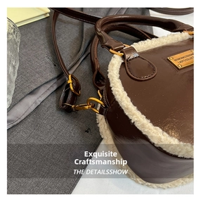 Close-up of brown leather handbag with faux fur trim and gold engraved metal plate