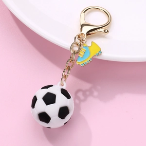 Soccer ball keychain with golden clasp and matching cleat charm on white plate