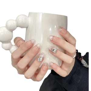 Pink cat-eye press-on nails with silver glitter and heart-shaped crystals on almond tips