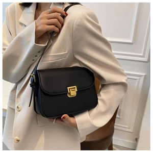 Dettaglio di una borsa a tracolla in pelle nera con fibbia quadrata dorata di tendenza