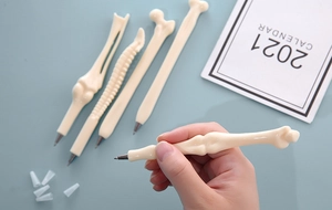 Detailed close-up of novel bone-shaped ballpoint pens with realistic plastic texture
