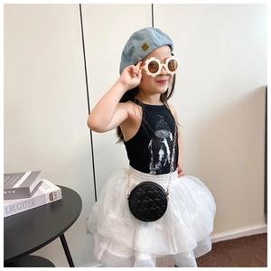 Detail of a girl wearing a black quilted heart chain bag and a blue denim beret