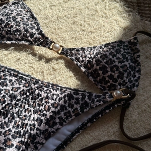Detail view of leopard print bikini set with gold metal rings and pearl embellishments