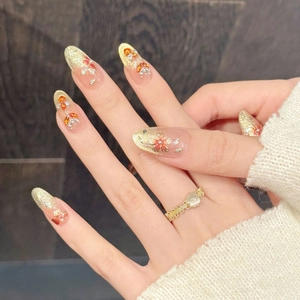 Close-up van roze en goud gradiënt kunstnagels met 3D-bloemen en kristallen details