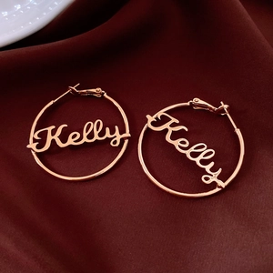 Detail of rose gold custom Kelly name hoop earrings on dark velvet background