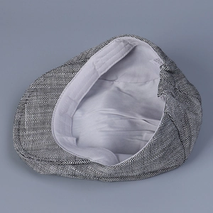 Detail view of herringbone flat cap interior featuring grey lining and washing label