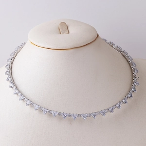 Detail of silver collar necklace with triangular zircon stones on a beige mannequin bust