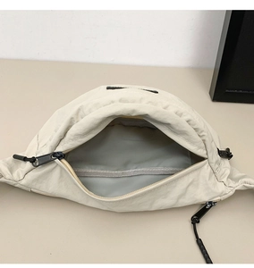 Detail view of the beige nylon chest bag main compartment with gray lining and zipper
