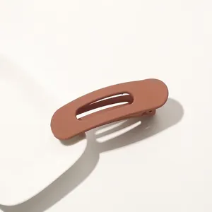 Detail of large matte brick red hair clip on ceramic dish with cutout design