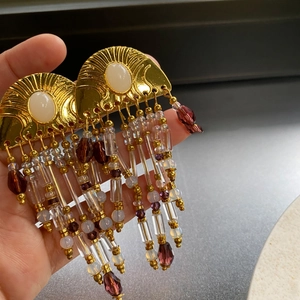 Close-up of vintage gold earrings with crystal tassels and purple teardrop beads