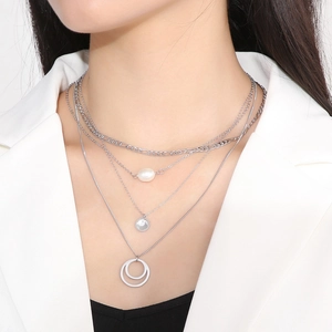 Detail of multi-layer silver necklace with pearls and crystal pendants on a female model