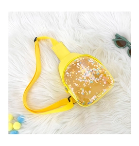 Detail of yellow kids chest bag with transparent sequin pocket on plush background