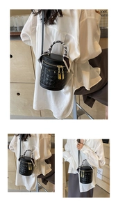 Detail of black woven bucket bag featuring gold hardware and elegant scarf-wrapped handle