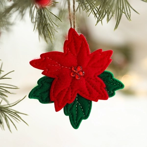 Poinsettia felt Christmas ornament with red petals and green leaves on pine branch