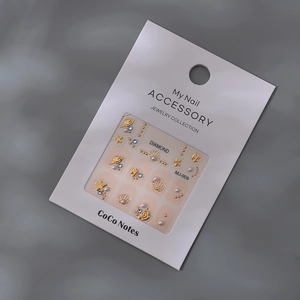 Detail of marine-style nail art charms with golden sea stars and pearls on display card