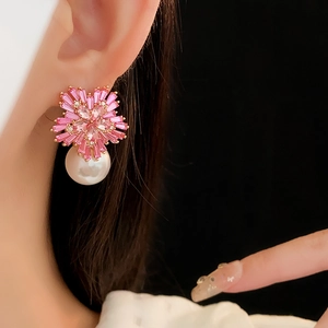 Close-up of rose gold flower earring with pink zircon, pearl on a model's ear