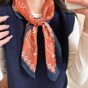 Detail of vintage orange and blue geometric pattern silk scarf tied in a classic neck knot