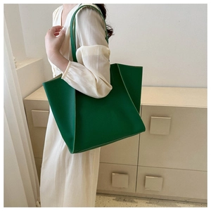 Lifestyle shot of model holding a large green leather tote bag with minimalist interior