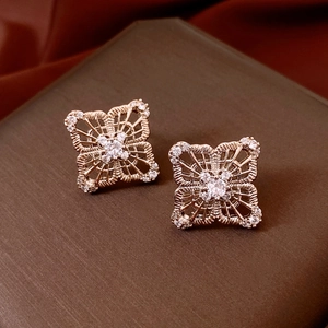 Macro detail of rose gold hollow floral earrings with shimmering zircons on brown box