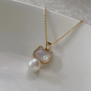 Macro shot of gold cat-shaped pendant with iridescent mother of pearl and round white pearl