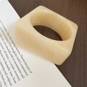 Detail view of cream marble resin square ring on vintage book and dark wood background