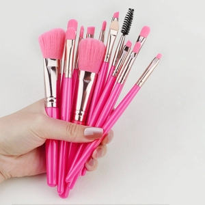 Close-up of pink makeup brush set held in hand featuring silver ferrules and synthetic hair